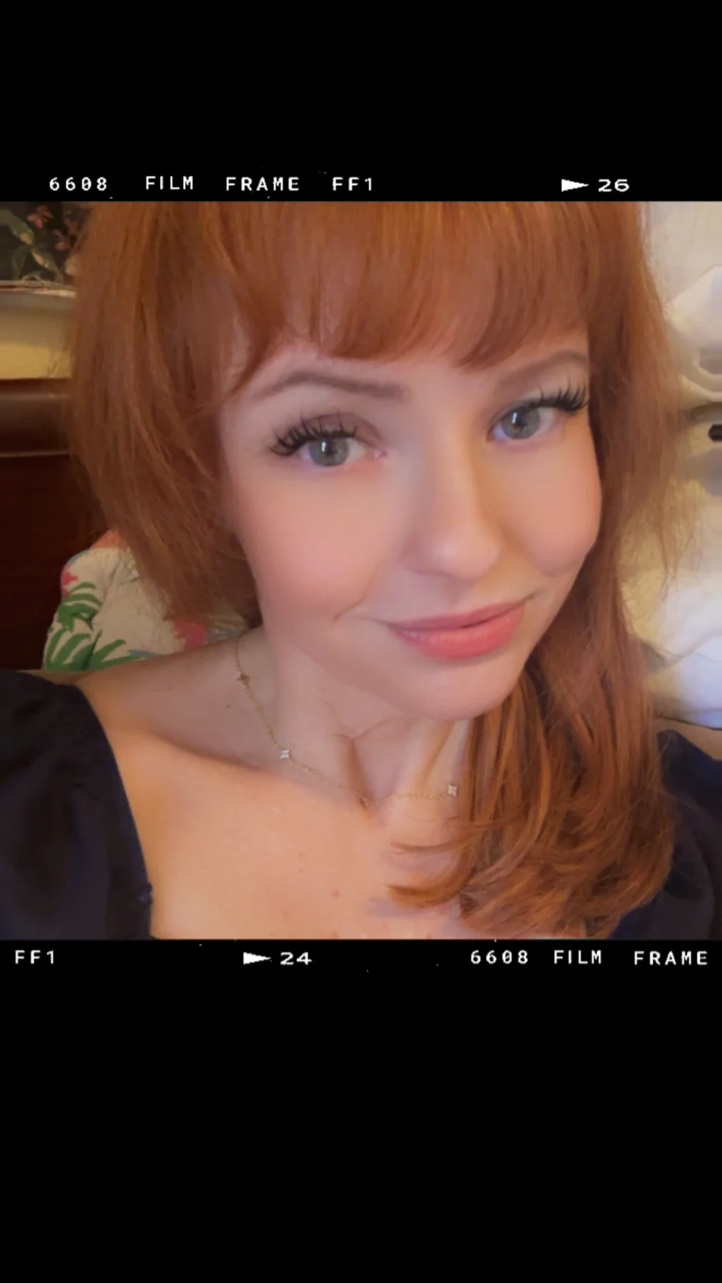 Audrey Mast with red hair and bangs, in a portrait with a black film-style border.