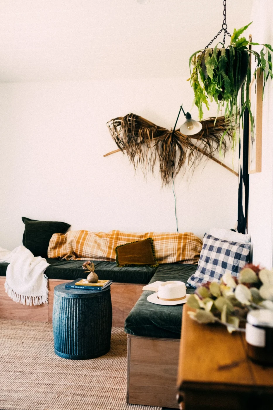 A living room with hanging plants, woven textures, and a mustard-colored sofa.