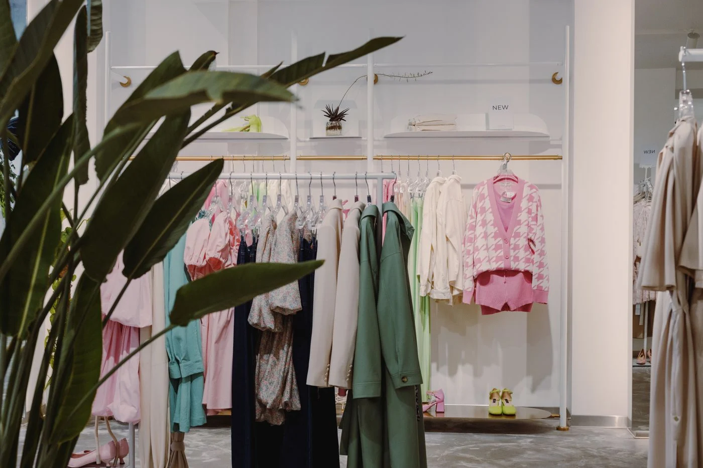 Colorful clothes on a boutique rack, with leafy plants in the foreground.