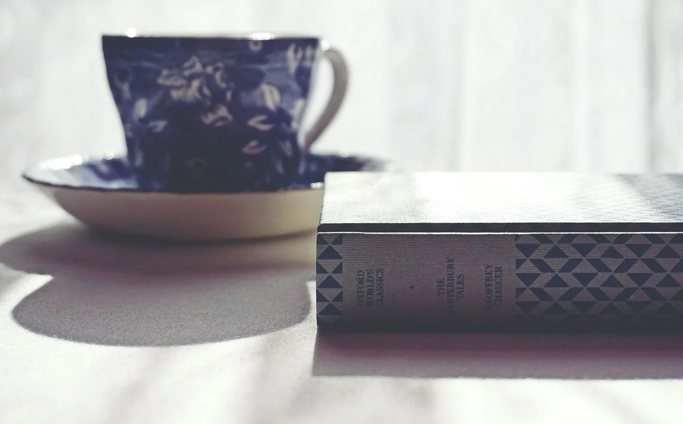 A blue floral cup and saucer beside a copy of The Canterbury Tales.